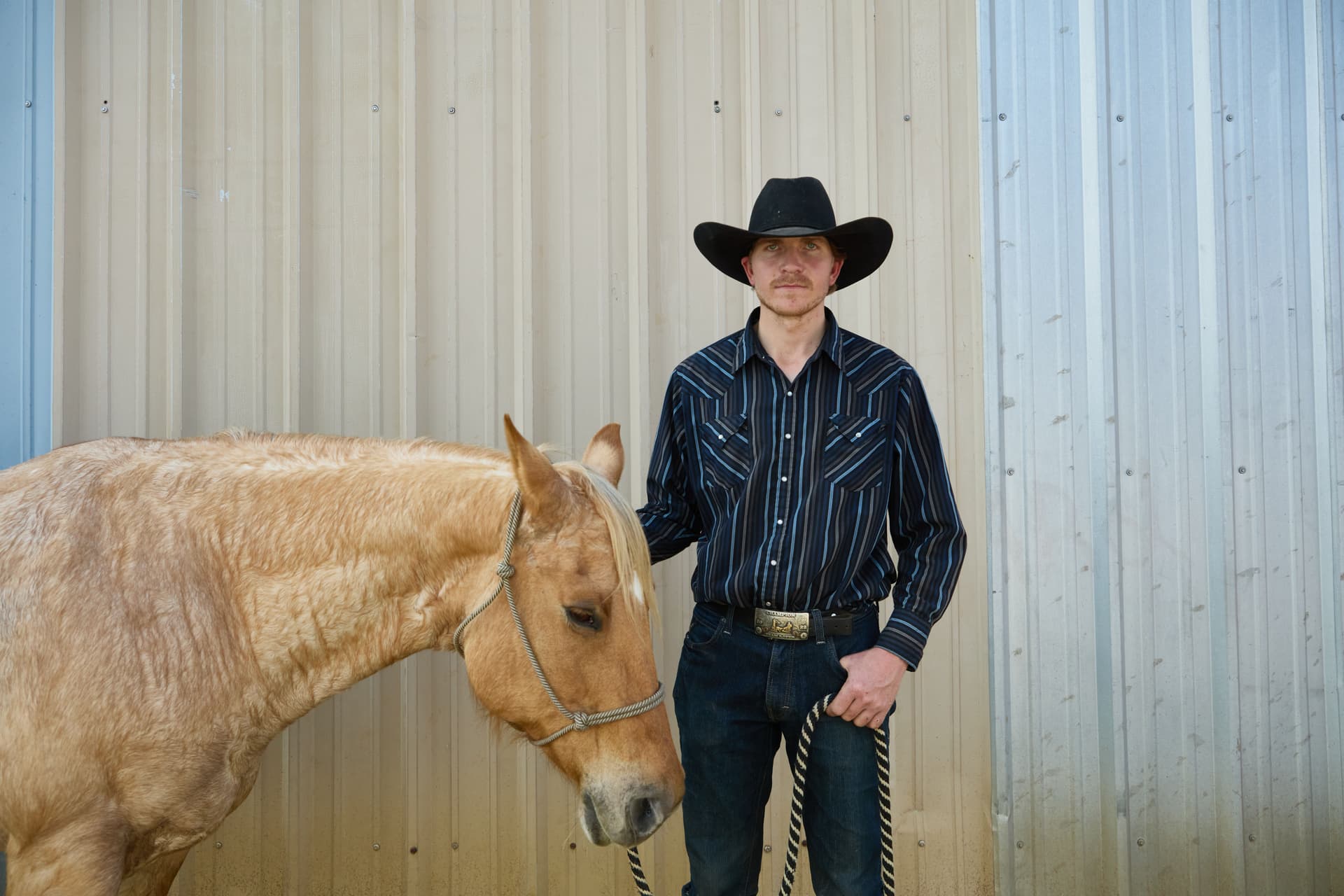 Cowboy and horse standing by a barn